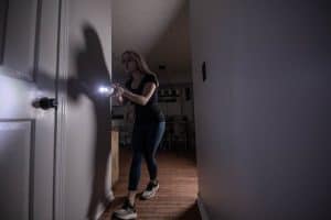 Women with Flashlight Self Defense Tool at Bedroom Door