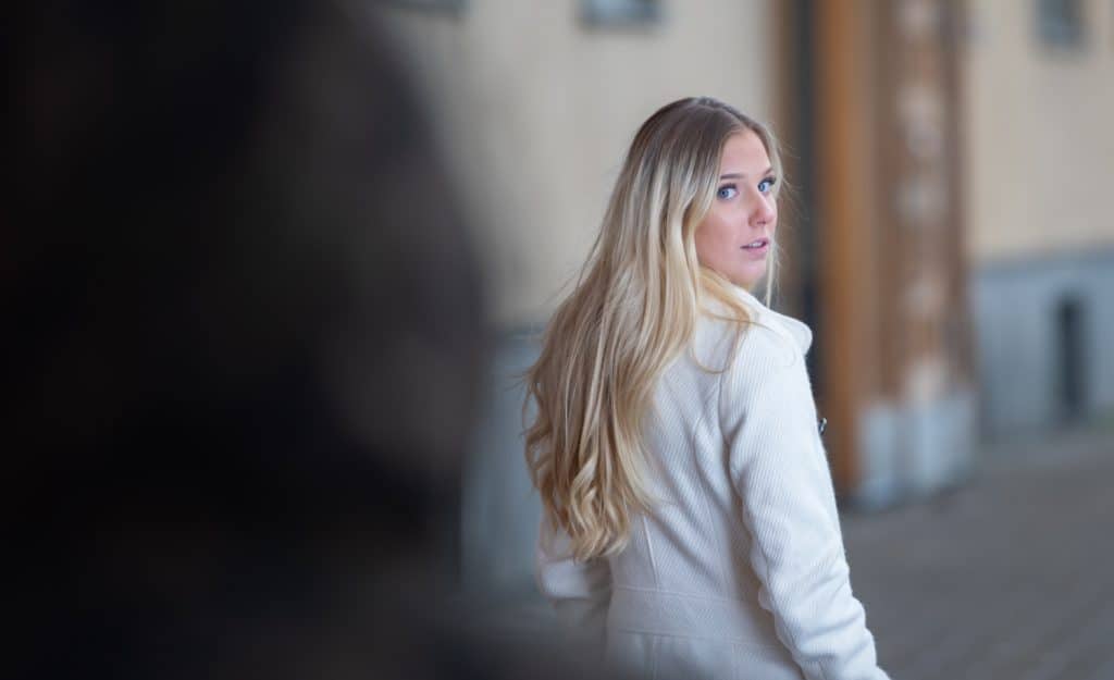 woman looking over her shoulder at a figure following her on the street.