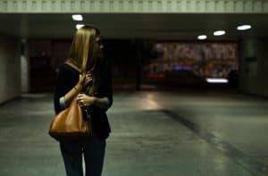 Women in a parking garage reaching for her hidden self defense weapon